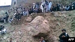 A video grab shows people watching the execution by gunfire of a 22 year old woman named as Najiba (not pictured) in Qol village, Parwan province.