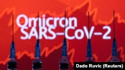 Syringes with needles are seen in front of a displayed stock graph and words "Omicron SARS-CoV-2" in this illustration taken, November 27, 2021. 