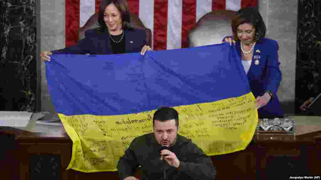 Potpredsednica SAD Kamala Haris (levo) i tadašnja predsednica Predstavničkog doma Nensi Pelosi dok ukrajinski predsednik Volodimir Zelenski poklanja poslanicima ukrajinsku zastavu sa autogramom trupa na liniji fronta u Bahmutu dok se obraća na zajedničkoj sednici Kongresa u Vašingtonu 21. decembra 2022. 