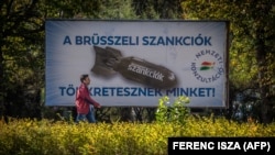 U Budimpešti 18. oktobra muškarac prolazi pored plakata na kojem je prikazana bomba, sa tekstom "Sankcije Brisela nas kažnjavaju".