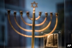 Menora za Hanuku izložena je uz fotografiju iz perioda kada je ovaj svijećnjak, koji je pripadao obitelji Posner iz Kiela, stajao uz prozor a nasuprot njega na fasadi ulice bila obješena nacistička zastava.