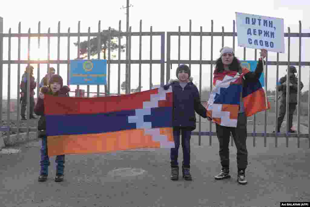 Armenians with a poster reading "Putin! Keep Your Word" stand in front of Russian peacekeepers at a checkpoint outside of Stepanakert on December 27. 