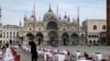 Un ospătar stand printer mesele goale la un restaurant din Piața San Marco din Veneția, Italia