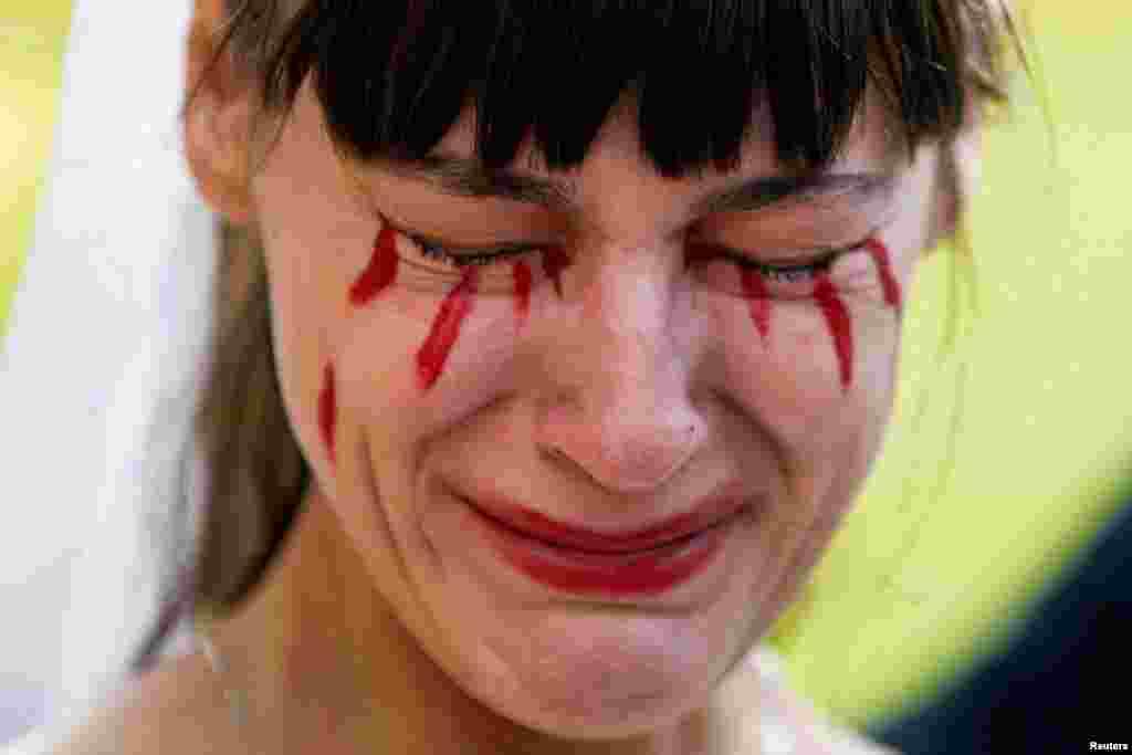 A woman with fake blood on her face reacts during a demonstration staged by supporters of Ukraine outside the Russian Embassy in Mexico City on February 26.