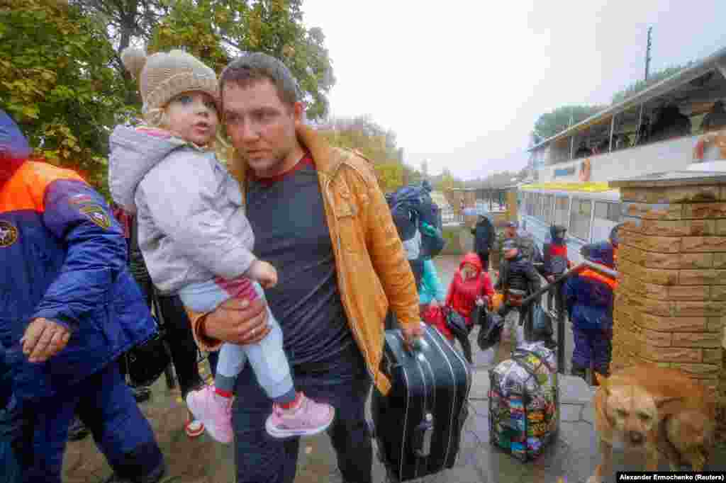 Мирные жители, эвакуированные из подконтрольного России города Херсона, идут от парома к автобусу 