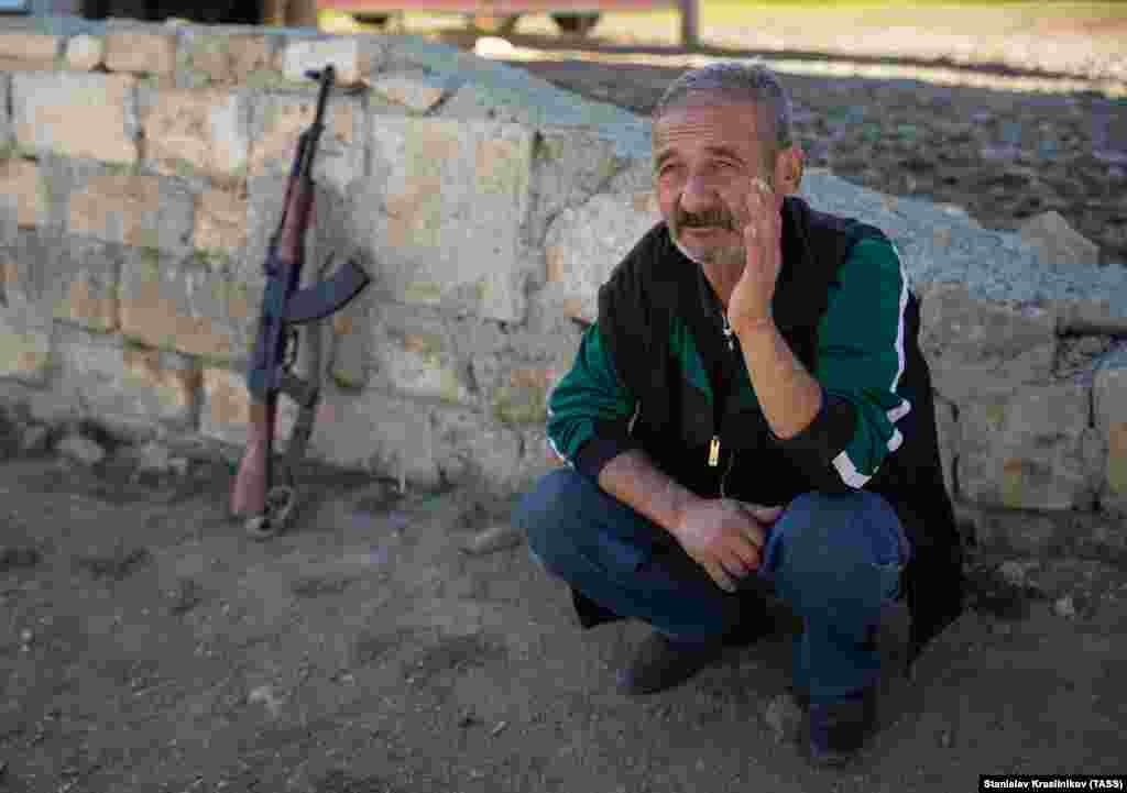 An elderly ethnic Armenian sits next to his weapon in Avetarnots. Some combatants in the current conflict have dusted off old weapons stored in their homes and last used in the Nagorno-Karabakh War that ended in 1994.