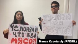 Студенты Карагоз Касым и Айсултан Кудайберген в международном аэропорту Алматы с плакатами для проведения акции против массового приезда россиян. 23 сентября 2022 года