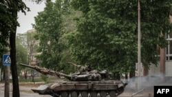 Ukrajinski borbeni tenk se kreće niz ulicu tokom granatiranja Severodonjecks u istočnoj Ukrajini (18. maj 2022)