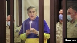Колишній президент Грузії Міхеїл Саакашвілі тримає свічку під час молитви за Україну на лаві підсудних під час судового засідання в Тбілісі, Грузія, 17 березня 2022 року