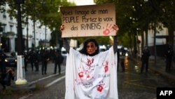  Učesnica protesta drži transparent sa natpisom "Ovo je slika mog naroda. Prenesite glas Iranaca", dok stoji ispred kordona policije tokom demonstracija podrške iranskim demonstrantima. U Parizu, 25. septembra 2022.