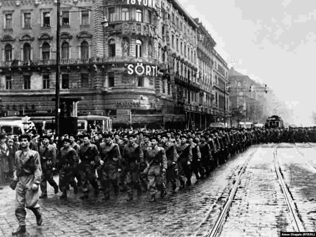 Марш камуністычнай рабочай міліцыі ў Будапэшце. Рабочая міліцыя была створана Камуністычнай партыяй Вугоршчыны пасьля аднаўленьня ёю кантролю над краінай. Асноўная мэта міліцыі – не дапусьціць паўтарэньня паўстаньня. Пасьля гвалтоўнага аднаўленьня кіраваньня краінай стаўленікамі СССР, Вугоршчыне давялося чакаць яшчэ 33 гады да зьмены намінальнай незалежнасьці на рэальную.