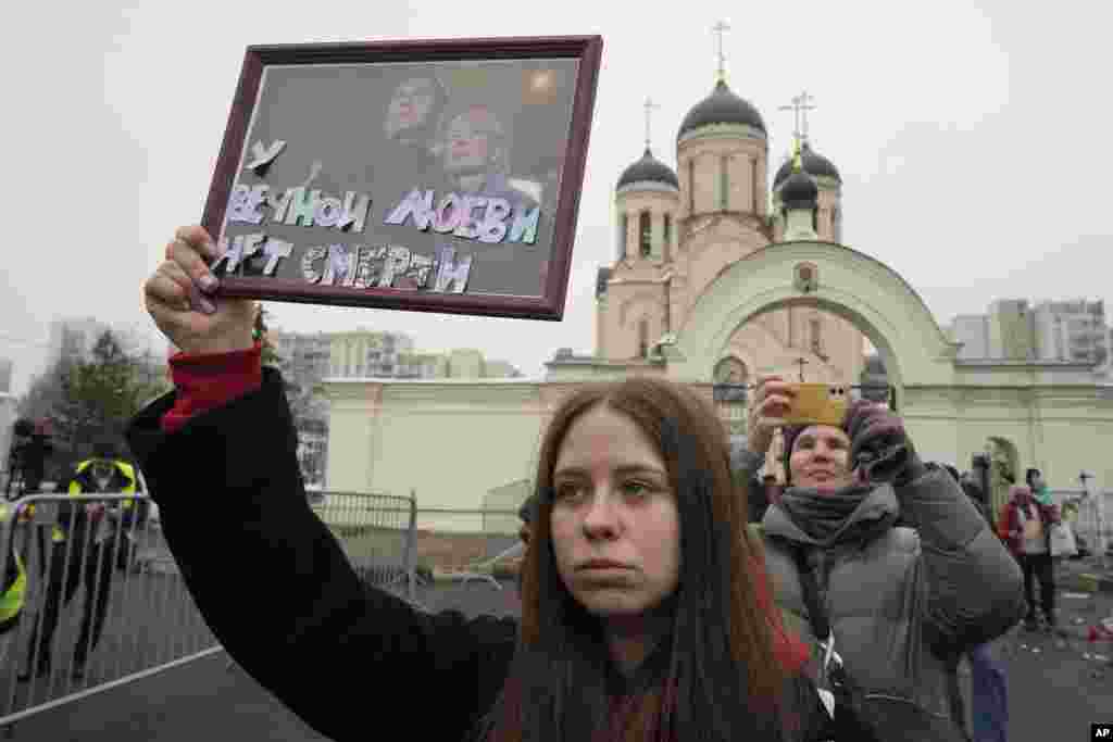 Дзяўчына трымае партрэт Аляксея Навальнага і ягонай жонкі Юліі з подпісам «У вечнага каханьня няма сьмерці», 1 сакавіка 2024 году