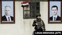 Руски военен стои между портретите на сирийския президент Башар ал-Асад (вдясно) и на руския президент Владимир Путин на контролно-пропускателен пункт в покрайнините на Дамаск, 1 март 2018 г.