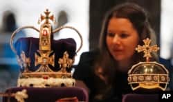 O femeie privește coroana și orbul Sfântului Eduard, expuse la Westminster Abbey, în Londra, 29 mai 2018. Până la încoronarea din 6 mai 2023, doar șase monarhi au purtat coroana de peste două kilograme în cele aproape patru secole.