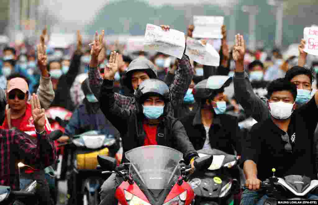 Motocicliștii arată salutul cu trei degete, un simbol al rezistenței, și țin semne pe care scrie „Aung San Suu Kyi liber” în timpul unui protest împotriva loviturii de stat militare din Naypyitaw, Myanmar, 7 februarie 2021.