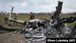 Українські сапери оглядають залишки російського гелікоптера, збитого біля аеропорту «Антонова» в Гостомелі на Київщині, 18 квітня 2022 року