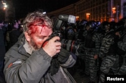 Поранений спецназом фотограф Reuters Гліб Гараніч фотографує, як спецназ блокує протестувальників на підтримку євроінтеграції на Майдані Незалежності в Києві, 30 листопада 2013 року