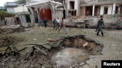 Afghan policemen walk past a crater at the site of a suicide attack at the Indian Consulate in Jalalabad on August 3.