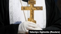 An Orthodox clergyman in Ukraine wears protective gloves, as a preventive measure against the coronavirus during a ceremony to bless Easter cakes earlier this week.