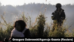 Польскія паліцыянты і памежнікі ахоўваюць групу мігрантаў, якія спрабавалі перасекчы мяжу паміж Беларусьсю і Польшчай каля вёскі Ўснар Горны, Падляскае ваяводзтва. 22 жніўня 2021 году. Ілюстрацыйнае фота