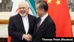 Chinese Foreign Minister Wang Yi (right) greets Iranian counterpart Mohammad Javad Zarif in Beijing on May 17.
