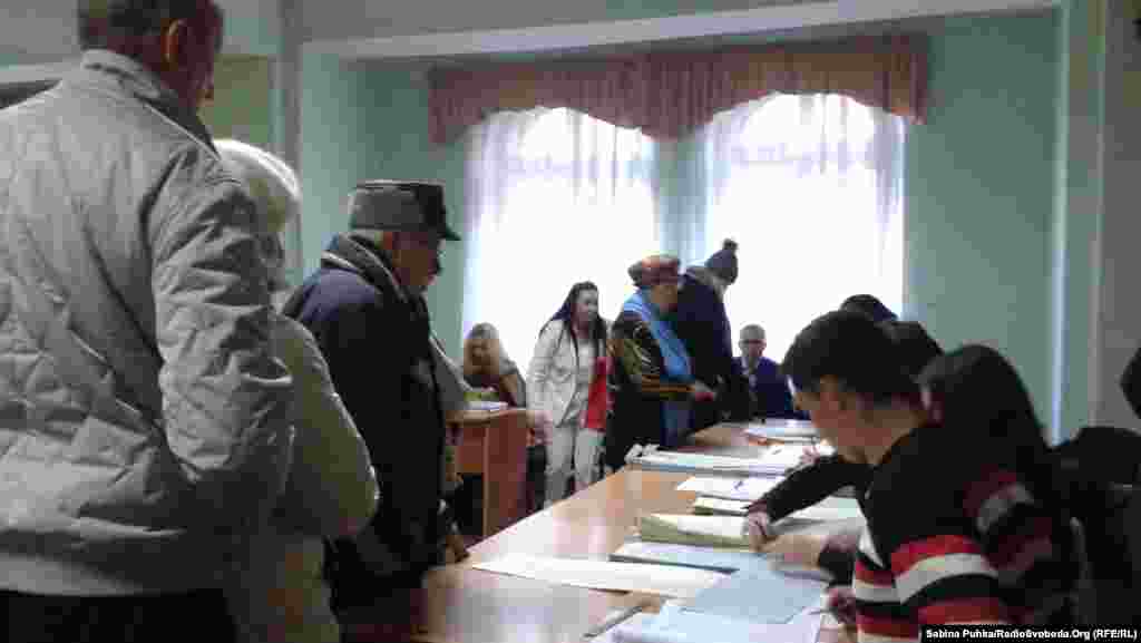 Украинада шайлоо бекеттери 26-октябрь күнү жергиликтүү убакыт боюнча эртең мененки саат 8де ачылды. Добуш берүү жергиликтүү убакыт менен кечки саат 8ге чейин уланат. Сүрөттө: Киевдеги шайлоо бекетине добуш бергени келген шайлоочулар. 26-октябрь, 2014-жыл. 