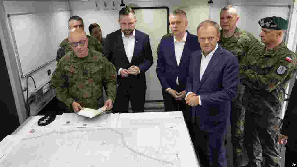 Poljski premijer Donald Tusk (prednji desno), ministar odbrane Wladyslaw Kosiniak-Kamysz (u sredini) i ministar unutrašnjih poslova Tomasz Siemoniak (desno u sredini) u posjeti vojsci u Dubicze Cerkiewni, na istoku Poljske, 29. maja. "Ovdje se ne bavimo (samo) bilo kakvim tražiocima azila, mi se bavimo koordinisanom, vrlo efikasnom na mnogim nivoima, operacijom probijanja poljske granice i pokušajima destabilizacije zemlje", rekao je Tusk.