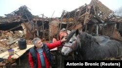 Farmer Tomislav Suknaić i njegov konj ispred porušene kuće u selu Majske Poljane, dan nakon razornog potresa koji je pogodio Hrvatsku (30. prosinca)