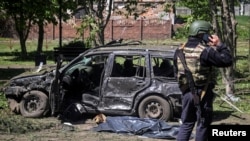 Поліцейський стоїть біля автівки, пошкодженої внаслідок російського обстрілу, Золочів, 1 травня 2023 року 