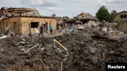 Люди стоять біля зруйнованих житлових будинків на місці російського ракетного удару в Покровську, Донецька область, Україна, 24 червня 2024 року