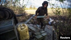 A Ukrainian soldier carries a shell to a tank at a position near a front line outside the town of Bakhmut.