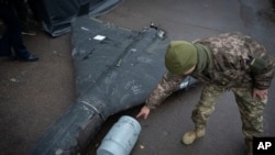 Украиналык жоокер Орусиянын атып түшүрүлгөн "Шахед" дронунун калдыгын көрсөтүүдө. 