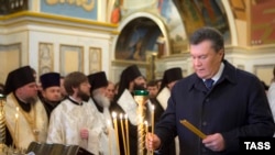 Президент Виктор Янукович Биримдик күнүнө карай чиркөөдө өткөрүлгөн зыяпатта шам койууда. Киев, 22-январь
