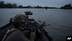 Украински войник в лодка на река Днепър на фронтовата линия край Херсон, Украйна. 