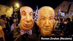 Demonstranti s maskama premijera Benjamina Netanjahua i ministra odbrane Benija Ganca na protestu u Jerusalimu, 8. avgust 2020.