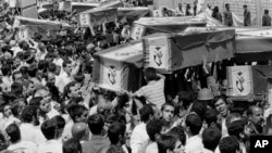 Mourners carry coffins through the streets of Tehran during a mass funeral for the victims of Iran Air Flight 655, which was shot down by the USS Vincennes in the Persian Gulf on July 7, 1988.