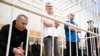 Trei avocați care l-au reprezentat pe politicianul de opoziție Alexei Navalnîi: Igor Sergunin (L), Aleksei Liptser (C) și Vadim Kobzev (R), în cușca acuzaților. 