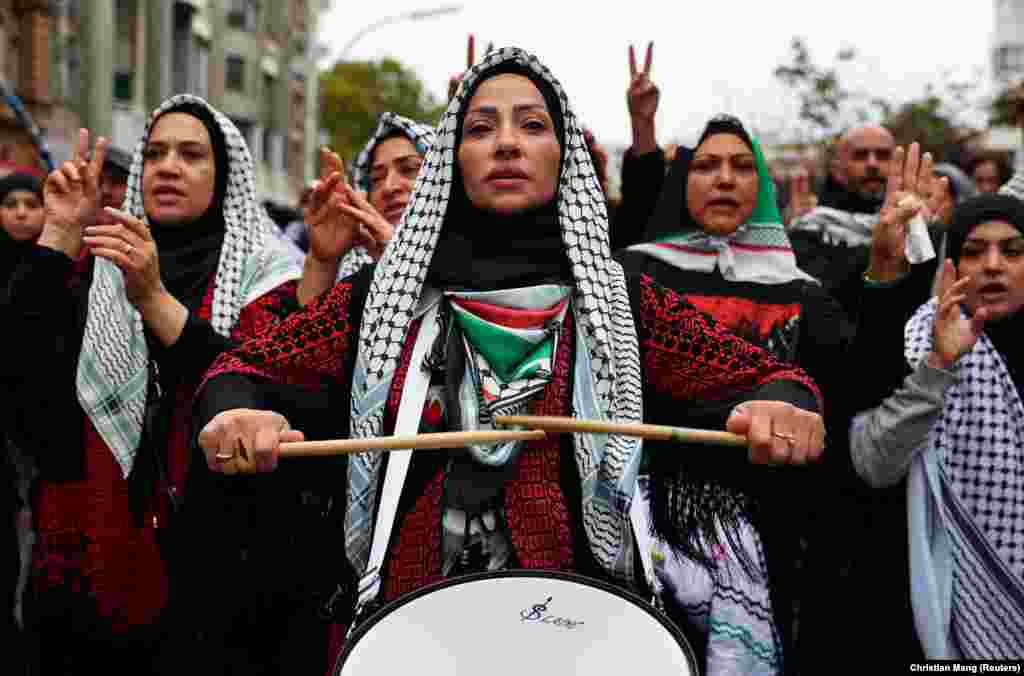 Učesnica protesta u Berlinu u Nemačkoj, lupa u bubnjeve, ogrnuta palestinskom maramom, 6. oktobar 2024.