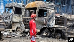 A rescue worker stands in front of burned vehicles after a massive explosion and fire rocked the Shahid Rajaei port near the southern port city of Bandar Abbas, Iran, on April 26