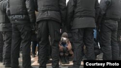 Айзат Абильсеит в окружении полицейского СОБРа в Алматы в день выборов в парламент.