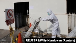 Медицински работник носи бутилка кислород. Снимката е от Румъния