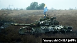 Донецк облусунда ташталган орус танкынын үстүндөгү украин желеги.