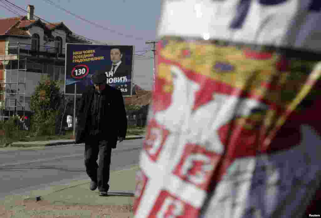 A Kosovar Serb walks past campaign posters for the Independent Liberal Party and Serbian Citizens' Initiative in the town of Gracanica.