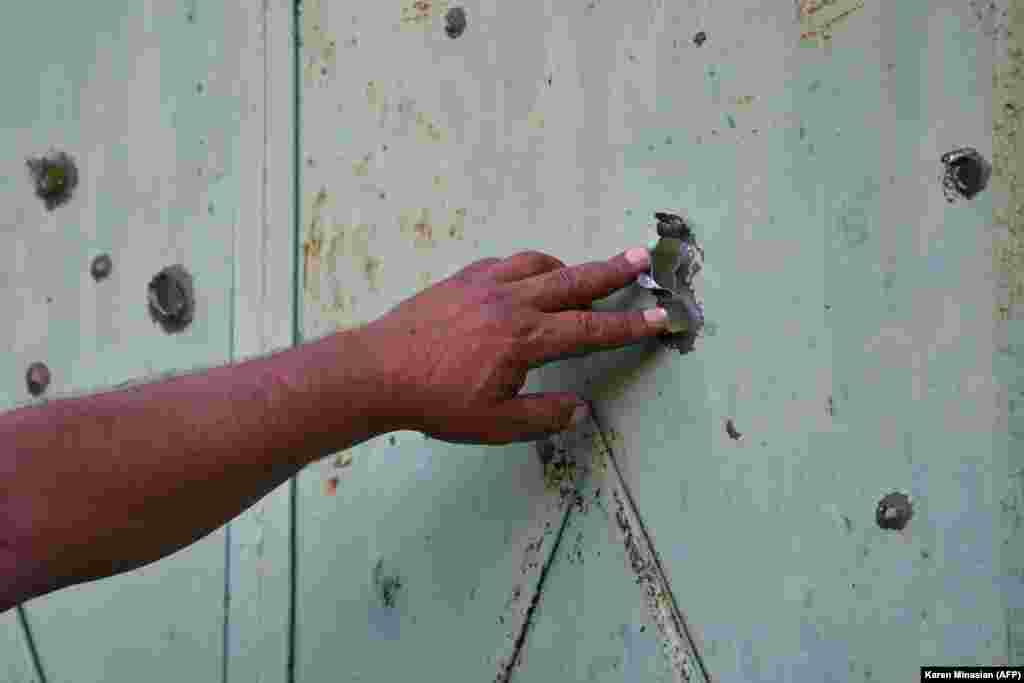 A resident of the Armenian village of Aygepar shows a gate damaged by shelling after July 15 clashes between Armenian and Azerbaijani forces.
