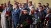 Ukrainian President Volodymyr Zelenskyy places flowers on the wall of a house destroyed by an April 24 Russian strike on a residential neighborhood of Kyiv that killed 12 people. 