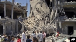 Predstavnici medija hodaju po ostacima oštećenih stambenih zgrada u Tripoliju, 19. jun 2011.