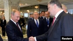 Президент Украины Петр Порошенко пожимает руку президенту России Владимиру Путину (слева) в присутствии президента Казахстана Нурсултана Назарбаева. Минск, 26 августа 2014 года.