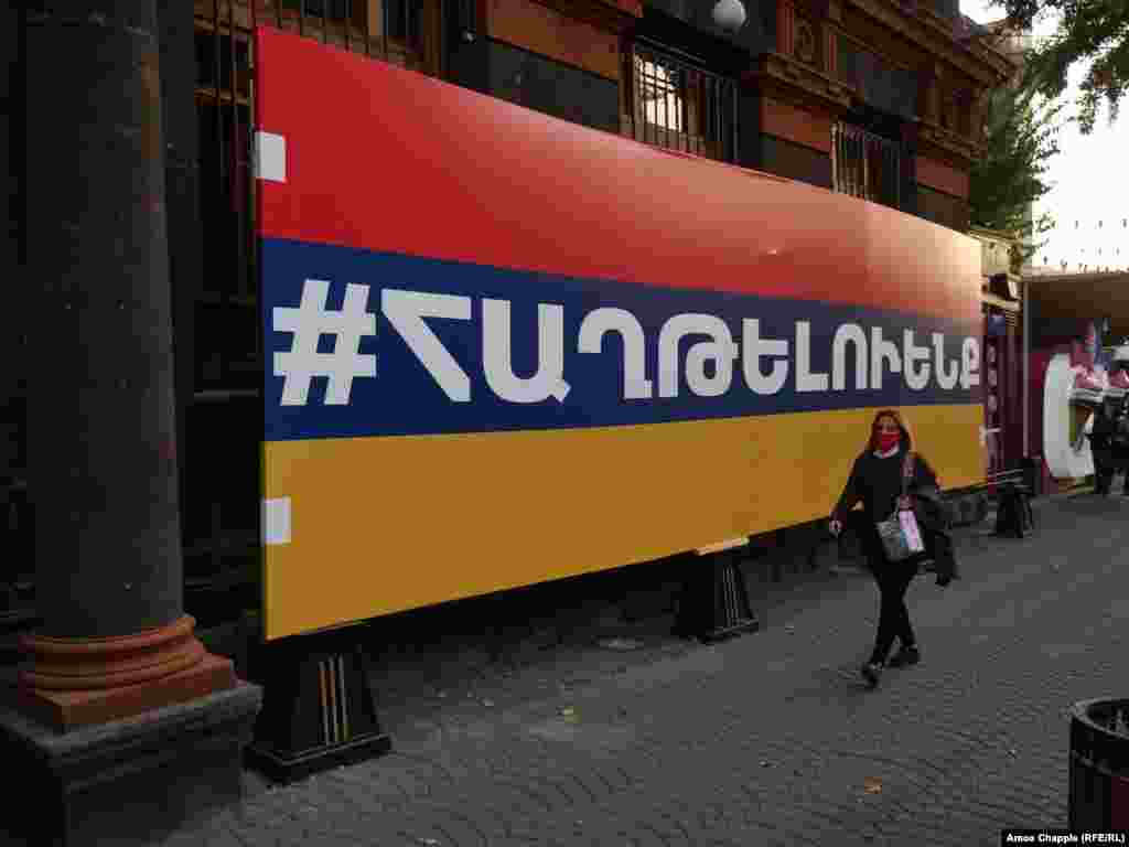 A woman walks past a large Armenian flag with the hashtag "we will win" on October 28. 
