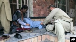 People attend to a man injured in a blast in the Afghan city of Mazar-e Sharif on March 11.