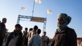 Afghan men stand near the Afghanistan-Iran border crossing of Islam Qala, on Nov. 24, 2021.